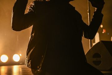 Photo du chanteur des Black Pumas assis sur le devant de la scène du zénith de Toulouse