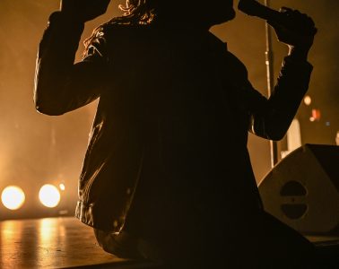 Photo du chanteur des Black Pumas assis sur le devant de la scène du zénith de Toulouse
