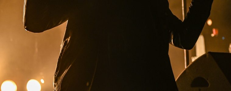 Photo du chanteur des Black Pumas assis sur le devant de la scène du zénith de Toulouse