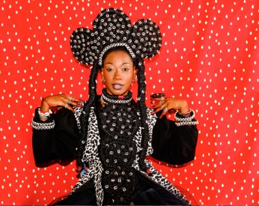 Portrait de Fatoumata DIawara sur fond rouge et costume folklorique