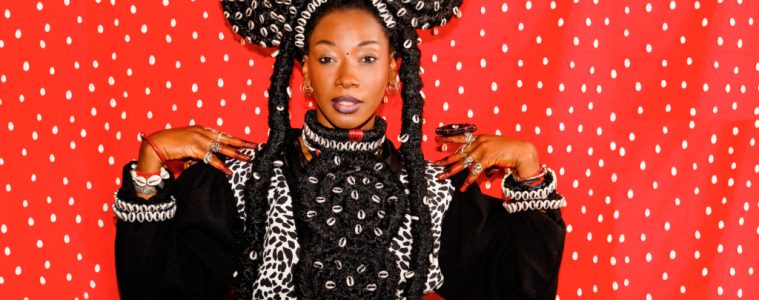 Portrait de Fatoumata DIawara sur fond rouge et costume folklorique